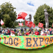 Port-Alberni-Forest-Rally-2016 Ralliers hold a large sign reading "Ban Raw Log Exports" in Port Alberni