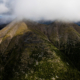 An aerial view of The Klinse-za (Twin Sisters) Mountains with grey, low hanging clouds hovering above them.