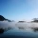 Morning mist hangs over Clayoquot Sound with mountains in the background.